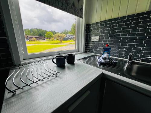 a kitchen counter with two coffee mugs and a window at Tigh Na Sealladh in Dunoon