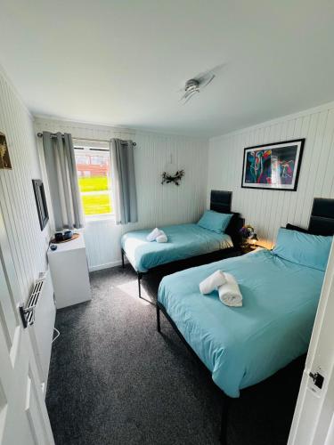 two beds in a room with blue sheets at Tigh Na Sealladh in Dunoon