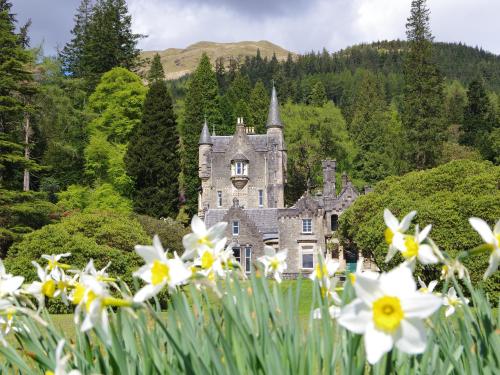 an old castle with flowers in the foreground at Ard Darach Lodge in Dunoon