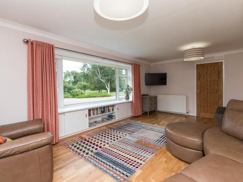 een woonkamer met een bank en een raam bij Sheeoch in Comrie