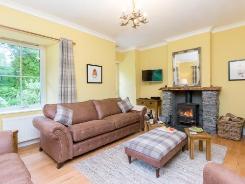 ein Wohnzimmer mit Couch und Kamin in der Unterkunft Grace's Cottage in Port of Menteith