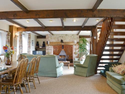 een woonkamer met een tafel en stoelen en een trap bij The Granary in Colyford