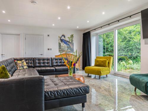 a living room with a leather couch and a yellow chair at The Aviary-Uk44382 in Callington