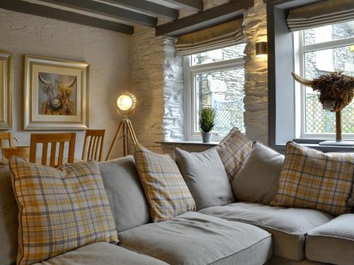 a living room with a couch and two windows at Grange End Coach House in Grasmere