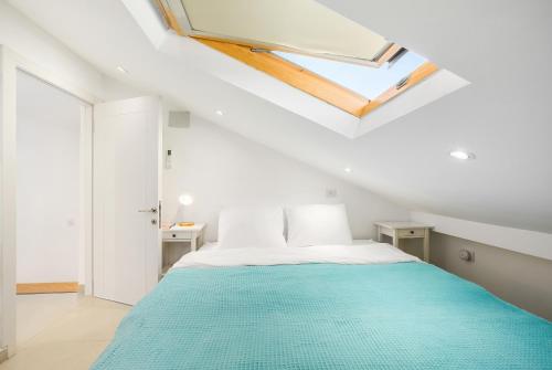 a white bedroom with a bed and a skylight at Sunny Hilltop Hideaway by Sea N' Rent in Tefahot