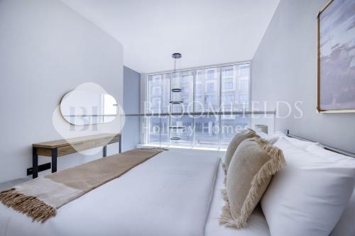 a white bedroom with a bed and a desk at Bloomfields Deluxe 1br Rukan in Nadd Shubayḩ