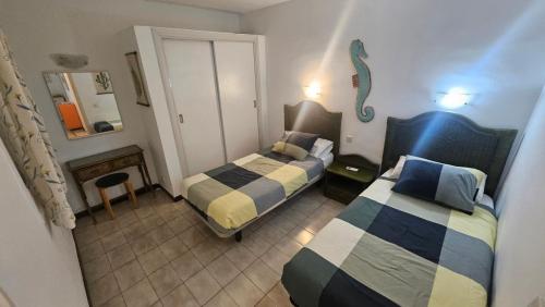 a small bedroom with two beds and a mirror at Bungalows Los Melocotones in Maspalomas