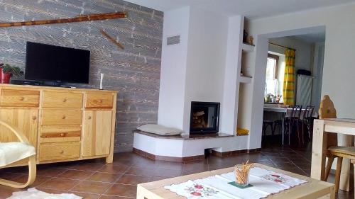 a living room with a fireplace and a tv at Chalupa Aja in Čierny Blh