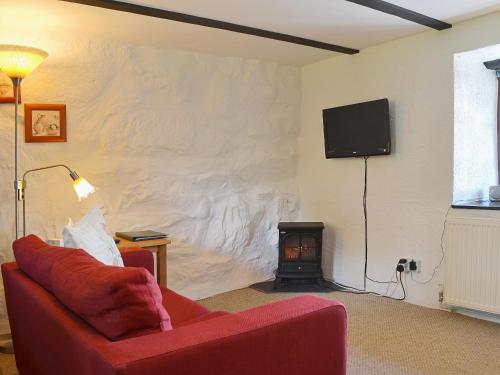 a living room with a red couch and a fire place at The Hayloft Barn in Criccieth