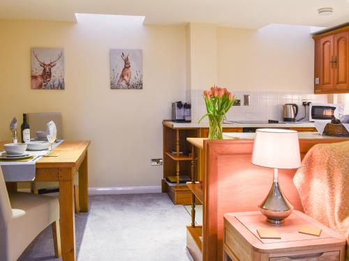 a kitchen with a desk and a table with a lamp at Stone Hill Oast Annexe in Egerton