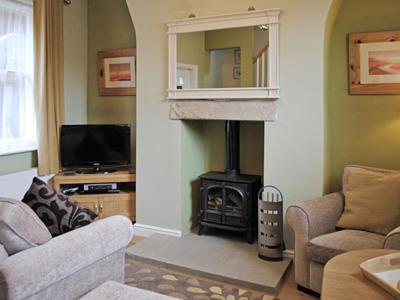 a living room with a fireplace and a stove at Cobweb Cottage in Whitby