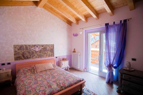 a bedroom with a bed and a window with purple curtains at Il Bosco dei 100 Acri in Roncobello