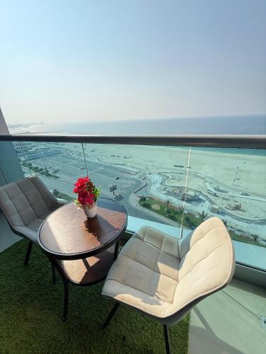 a balcony with two chairs and a table and a view at Full seaview luxury with gym,pool,jacuzzi,sauna,24x7 cafe,beach,restaurants,medical and more in Ajman 