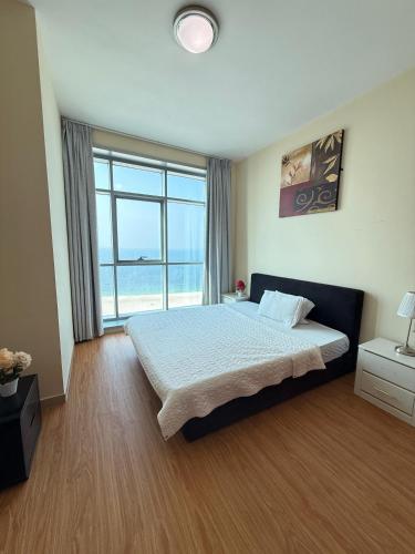 a bedroom with a bed and a large window at Full seaview luxury with gym,pool,jacuzzi,sauna,24x7 cafe,beach,restaurants,medical and more in Ajman