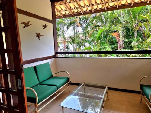 Zimmer mit grünem Sofa und großem Fenster in der Unterkunft Apartamento duplex em Praia do Forte - 2 suítes in Praia do Forte