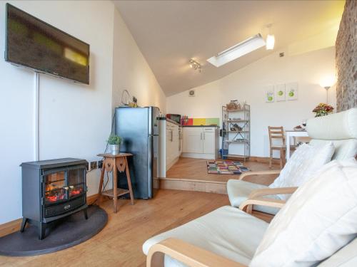 a living room with a stove and a refrigerator at Old Orchard Barn - The Annexe in Buckland St Mary