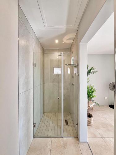 a glass shower in a bathroom with white walls at Blouberg Village Place in Cape Town