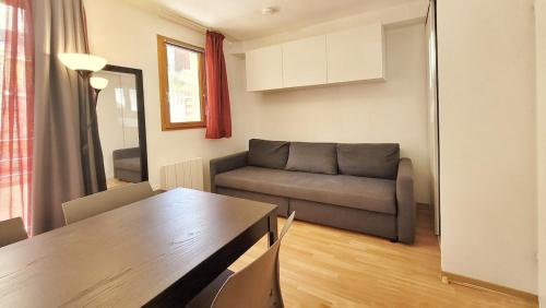 a living room with a couch and a table at Studio tout équipé, piscine chauffée, départ skis aux pieds in Les Orres