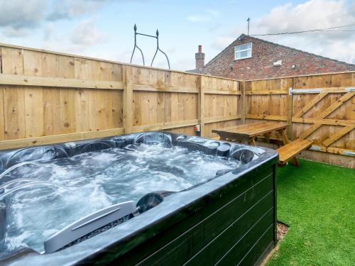 a hot tub in a backyard with a wooden fence at Farriers Lodge in Burshill