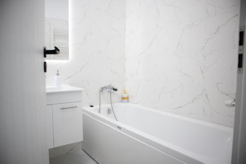 a white bathroom with a tub and a sink at Garsonieră Studio in Dudu