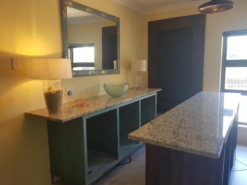 a bathroom with a counter with a sink and a mirror at 4th On Boundary in Gordonʼs Bay