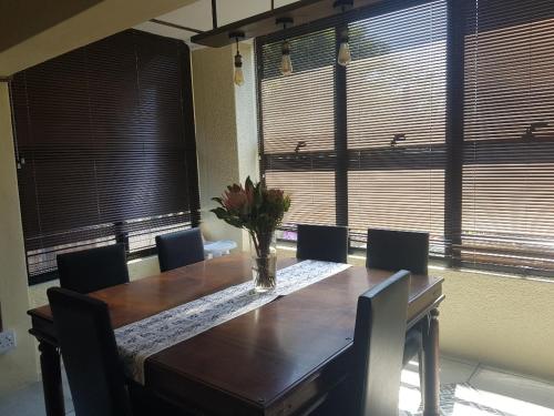 a dining room with a wooden table with chairs and windows at 4th On Boundary in Gordonʼs Bay