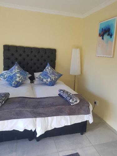 a bedroom with a bed with blue and white pillows at 4th On Boundary in Gordonʼs Bay
