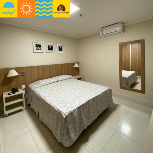 ein Schlafzimmer mit einem großen Bett und einem Spiegel in der Unterkunft Piazza diRoma com acesso ao Acqua Park - Heloísa Cn in Caldas Novas