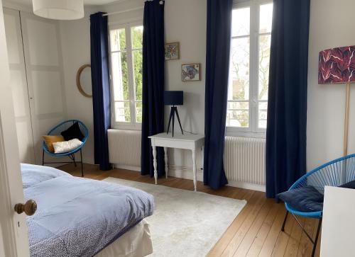 une chambre avec des rideaux bleus et un lit et deux chaises dans l'établissement Gîte Avec Piscine La Petite Gironde, à Porchères