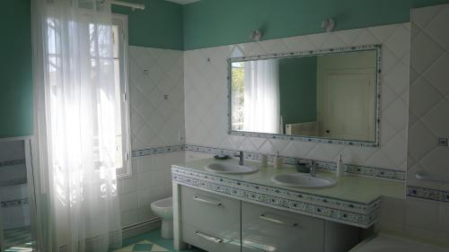 une salle de bain avec deux lavabos et un miroir dans l'établissement Gîte Avec Piscine La Petite Gironde, à Porchères