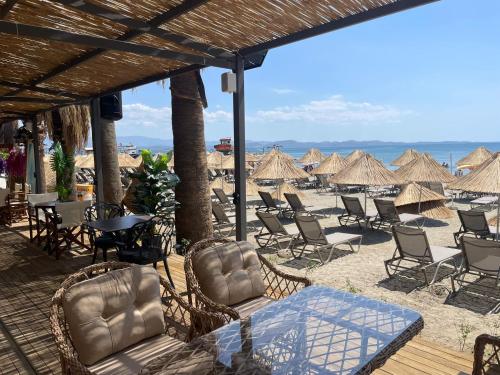 a group of chairs and tables and umbrellas on a beach at Grand Cennet Beach Hotel in Akcay