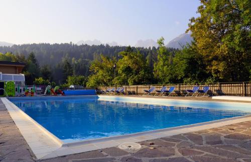 Una gran piscina azul con sillas y árboles. en Sporting Hotel Club, en Pelos