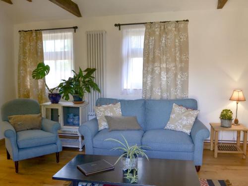 a living room with a blue couch and two chairs at Cowslip Cottage Ukc1898 in Dogdyke