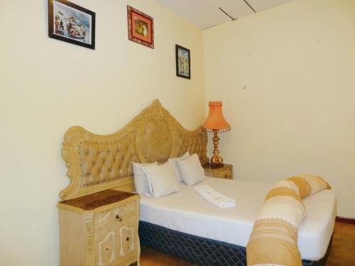 a bedroom with a white bed with a wooden headboard at Pro Max Guesthouse Goodwood in Goodwood