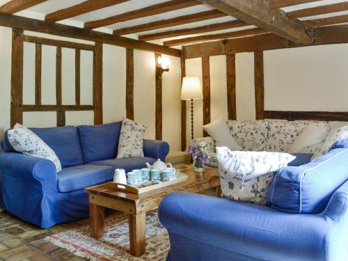 a living room with blue couches and a coffee table at Meadow Cottage in Chediston