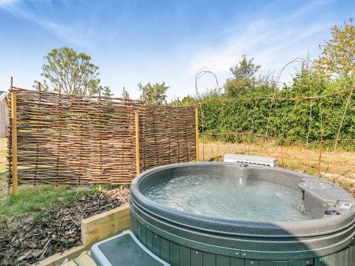a hot tub in a yard next to a fence at Fuchsia Lodge in Willington