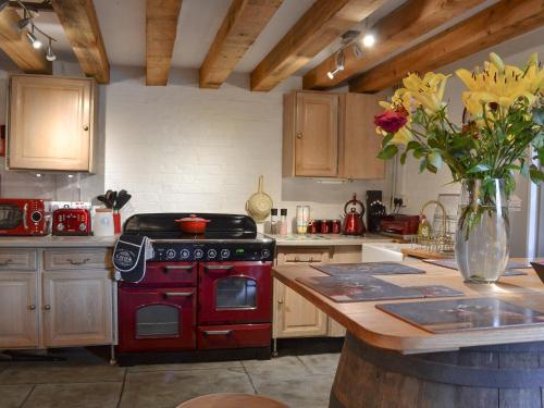 a kitchen with a red stove and a vase of flowers at Meadow Barn in Ellingham
