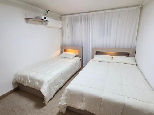 Dos camas en una habitación pequeña con paredes blancas. en Exit 4 of Hongik University, en Samgong-ni