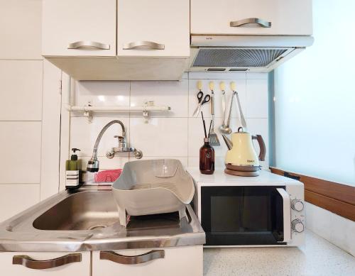 una cocina con fregadero y una silla. en Exit 4 of Hongik University, en Samgong-ni