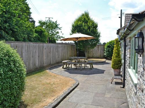 a patio with a picnic table and an umbrella at Bluebell Cottage - E4741 in Chipping Sodbury
