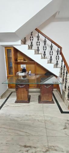 uma mesa de vidro num quarto com uma escada em The Duplex House HSR em Bangalore