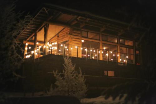 a cabin with christmas lights on the balcony at night at Hébergement Mauricie, La Tuque in La Tuque