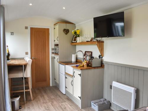 Una cocina con un fregadero y un televisor en la pared. en Greengill Farm Shepherds Hut- Ukc3632, en Gilcrux