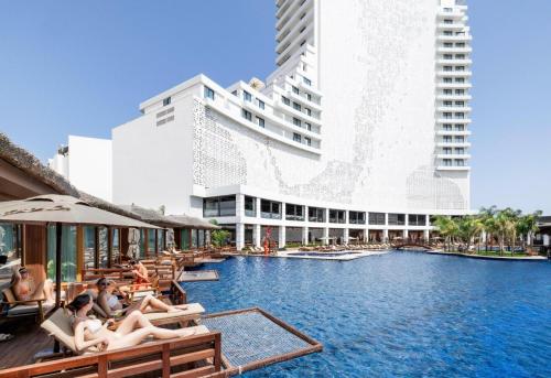 a hotel with a swimming pool with people sitting in chairs at Grand Sapphire Hotel, Casino & Spa Holiday Deluxe Residential Home in Iskele