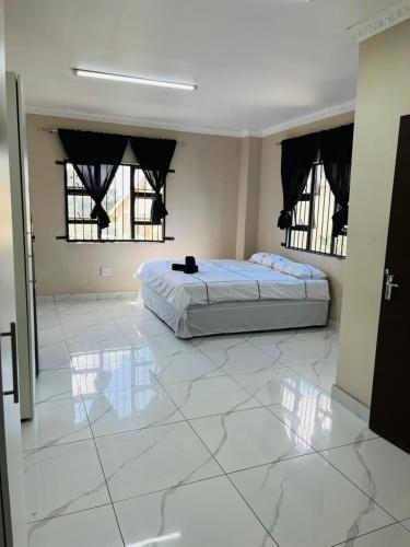 a bedroom with a bed and two windows on a tiled floor at Sunset in Durban