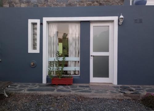 a blue house with a door and a potted plant at Alojamiento Temporario El Nogal in Tandil