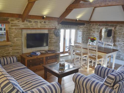 a living room with couches and a table and a television at The Stables By The Sea in Newquay