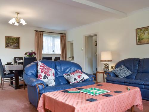 ein Wohnzimmer mit einem blauen Sofa und einem Tisch in der Unterkunft Oak Tree Cottage - E5062 in Lydbrook