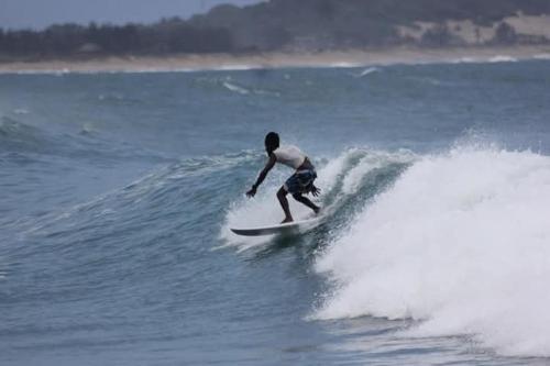 a man riding a wave on a surfboard in the ocean at Robbo's Surfcamp in Arugam Bay