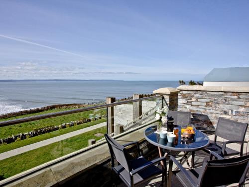 een balkon met een tafel en stoelen en de oceaan bij 4 Ocean Point in Croyde